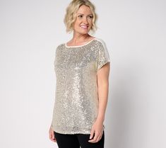 a woman standing in front of a white wall wearing black leggings and a gold sequin top