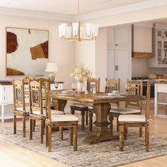 a dining room table with chairs and a rug on the floor in front of it