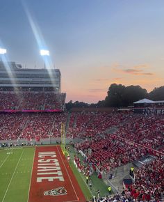 a football stadium filled with lots of people watching the sun go down in the distance