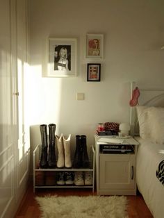 a bedroom with white walls and wooden flooring next to a small table filled with shoes