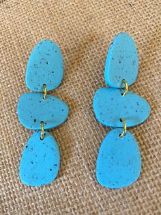 two pairs of blue earrings sitting on top of a piece of cloth