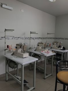 several sewing machines are lined up in a room with tables, chairs and other items