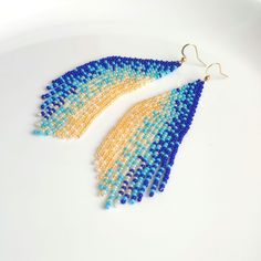 These long beaded earrings feature a vertical gradient transitioning from blue to yellow hues. Handmade with meticulous attention to detail, they exude sophistication and elegance. Perfect for completing your ensemble with chic and style. Dimensions: - Length: 10 cm (3.9 inches) - Width: 3 cm (1.2 inches) Blue Tassel Earrings For Festivals, Blue Tassel Drop Earrings For Festival, Festival Blue Chandelier Earrings With Colorful Beads, Bohemian Blue Long Drop Beaded Earrings, Blue Long Drop Chandelier Earrings, Long Chandelier, Beaded Fringe Earrings, Yellow Hues, Native American Beaded Earrings