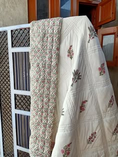 a white quilted bed sitting on top of a wooden floor next to a window