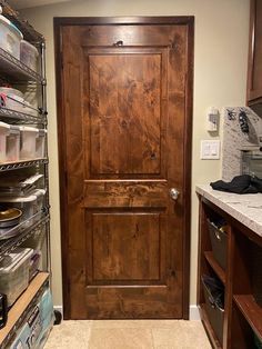 a wooden door sitting inside of a kitchen next to a shelf filled with boxes and other items