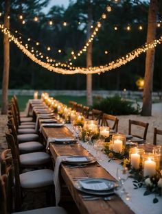 a long table is set with candles, plates and place settings for an outdoor dinner