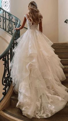 a woman in a wedding dress walking down some stairs with her back to the camera