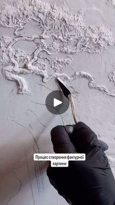 a person in black gloves painting a wall with white paint