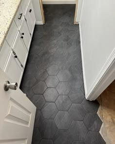 a bathroom with black hexagonal tiles on the floor and white cabinets in it