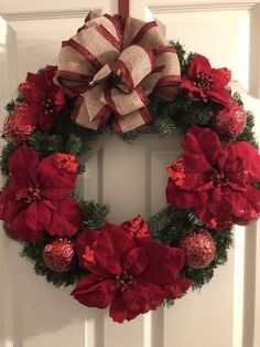 a christmas wreath with poinsettis hanging on the front door