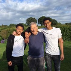 three men standing next to each other in the grass