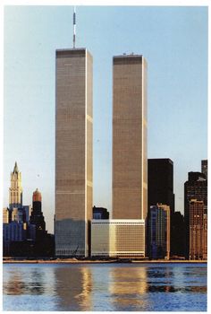 two tall skyscrapers in the middle of a large body of water with buildings around them