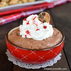 a red bowl filled with chocolate pudding and whipped cream on top of a wooden table