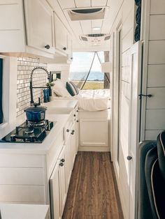 the interior of a small camper with wood flooring and white cabinets on both sides