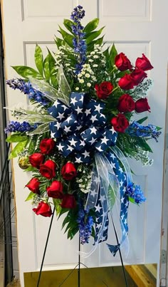 a patriotic wreath with red, white and blue flowers on it in front of a door