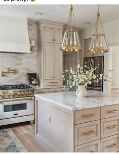 a large kitchen with an island and two lights hanging over the stove top, surrounded by white cabinets