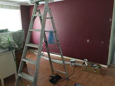 a ladder that is sitting in the middle of a room with purple walls and wood floors