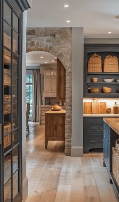 an open kitchen with wooden floors and cabinets in the center, along with baskets on the counter