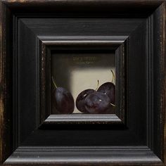 two black cherries in a wooden frame