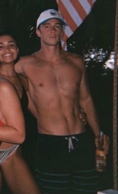 a man and woman in bathing suits standing next to each other with an american flag behind them