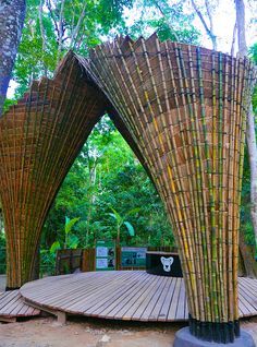 two wooden structures in the middle of a forest with trees and benches around them, all made out of bamboo sticks