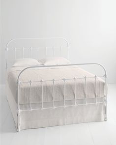 a white metal bed frame with two pillows