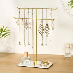 a gold jewelry stand with earrings and other accessories on it, next to a mirror