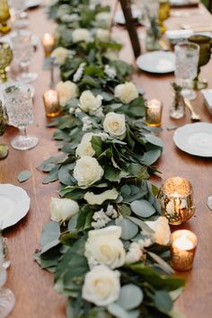 a long table with white flowers and greenery is set up for a formal dinner