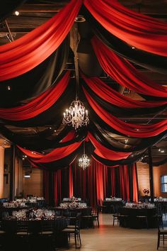 a banquet hall decorated with red drapes and chandelier hanging from the ceiling