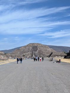 people are walking around in front of an ancient pyramid on a clear day with blue skies