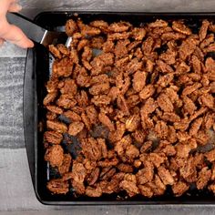 a person is holding a spatula over a tray full of fried food on the table