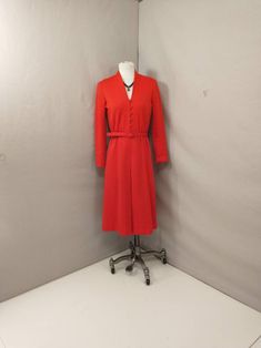 "Wonderful styling and dramatic red color. Quality mid weight polyester fabric and quality construction. Hand washable and washed. The label is cut off, retains its Union made label. Shape ilong sleeves. Size unmarked please go by measurements. Shown on a 6 dress form. Condition very good, light discoloration on buttons and belt buckle. Length 44\" Shoulder to waist 16.5\" Shoulder 16\" Bust 38\" Waist 25-32\" elastic  Hips 41\" Hem Circumference 62\" Sleeve length 22\" Wt 17oz 2 lb to ship" How To Make Labels, 70s Dress, Union Made, Polyester Dress, Dress Form, Dress Clothes For Women, Deep V Neck, Deep V, Polyester Fabric