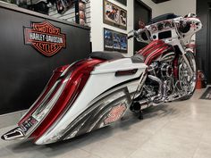 a red and white motorcycle parked inside of a garage next to a wall with pictures on it