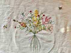 a bunch of flowers that are sitting on a table cloth with bees flying around them