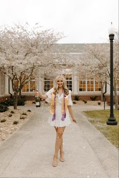 a woman standing on a sidewalk in front of a building with cherry trees and flowers