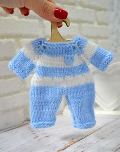 a baby's blue and white knitted outfit hanging from a hook