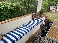 a blue and white striped bench sitting on top of a wooden deck