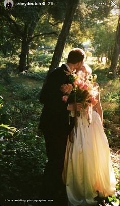 a bride and groom are kissing in the woods with flowers on their wedding day,