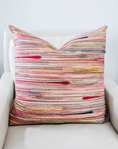 a white chair with a colorful pillow on it