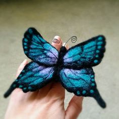 a hand holding a blue and purple butterfly