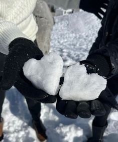 two people holding out their hands with snow in the shape of hearts on them,