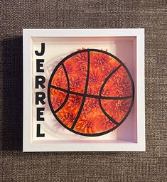 a basketball in a shadow box with the word jerrel on it's side