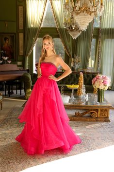 a woman in a pink dress standing next to a chandelier