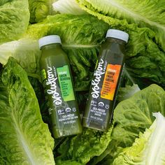 two bottles of juice sitting on top of lettuce