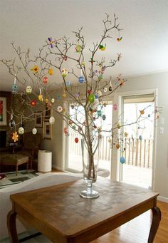 a table with a vase filled with ornaments on top of it and a tree in the middle