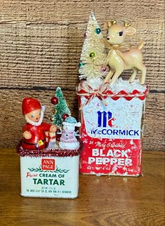 an old fashioned christmas box with a small figurine next to it on a wooden table