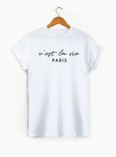 PLEASE NOTE: ALL SHIRTS IN THIS SHOP ARE UNISEX SIZING. REFER TO SIZING CHART AVAILABLE IN IMAGES. C'EST LA VIE SHIRT -------------- For every item purchased we donate $1 to an organization helping establish schools and education infrastructure in developing countries. It's our way of giving back! -------------- Available in sizes S-XL in a variety of shirt and text colors. Please refer to sizing chart for specific measurements. -------------- All items are made-to-order from our at-home studio. Newlywed Shirts Honeymoon, Paris Tee, Catch Flights, Paris Shirt, Wedding Shirt, Honeymoon Shirts, Slogan Shirts, Travel Tees, Feminist Shirt