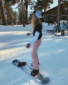 a woman riding a snowboard on top of a snow covered slope next to trees