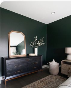 a living room with green walls and a large mirror on the wall next to a dresser