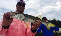 a man holding a fish while standing on a boat